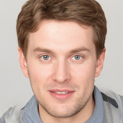 Joyful white young-adult male with short  brown hair and blue eyes