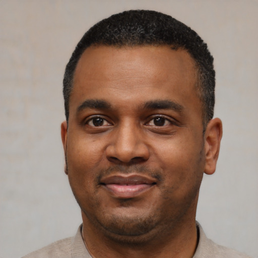 Joyful black young-adult male with short  black hair and brown eyes