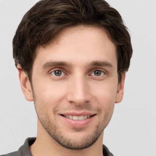 Joyful white young-adult male with short  brown hair and grey eyes