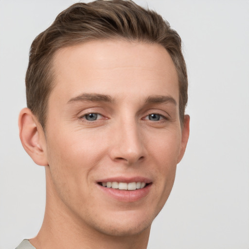 Joyful white young-adult male with short  brown hair and grey eyes