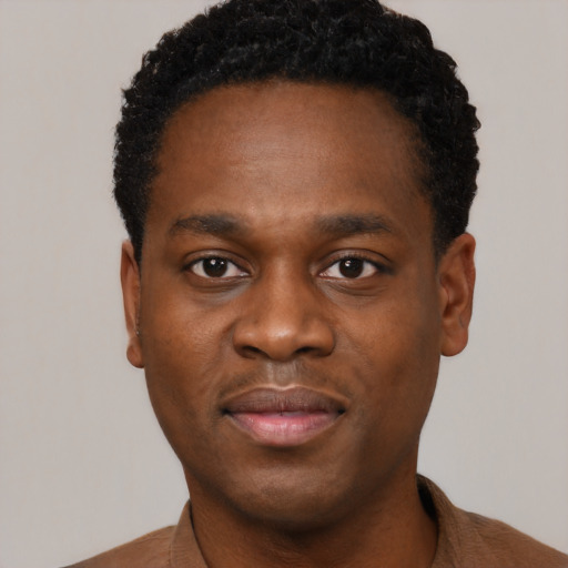 Joyful black young-adult male with short  black hair and brown eyes