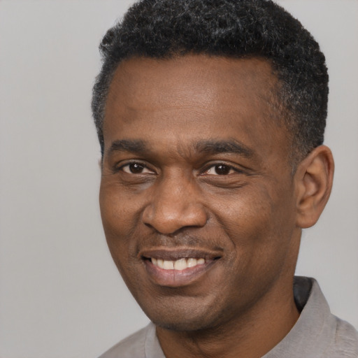 Joyful black adult male with short  black hair and brown eyes
