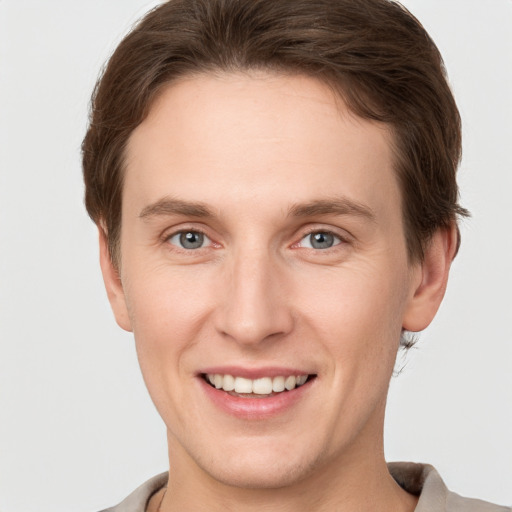 Joyful white young-adult male with short  brown hair and grey eyes