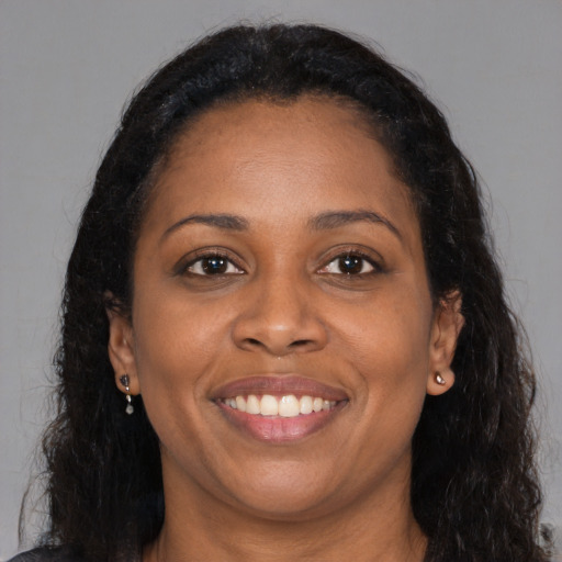 Joyful black adult female with long  brown hair and brown eyes