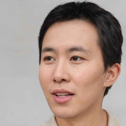 Joyful asian young-adult male with short  brown hair and brown eyes
