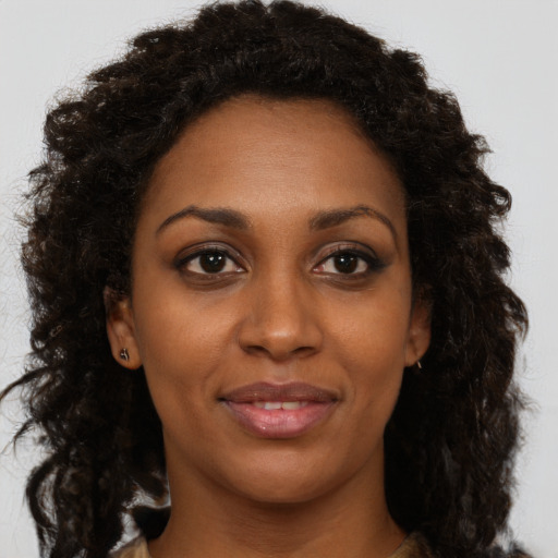 Joyful black young-adult female with long  brown hair and brown eyes