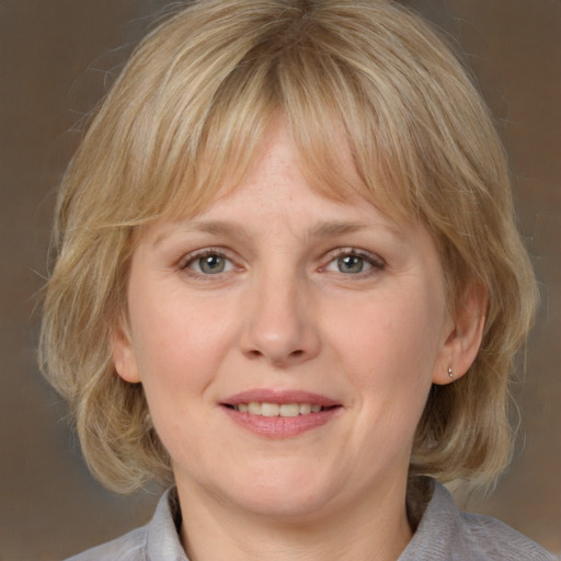 Joyful white adult female with medium  blond hair and grey eyes