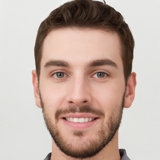 Joyful white young-adult male with short  brown hair and grey eyes