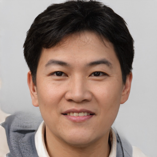 Joyful asian young-adult male with short  brown hair and brown eyes