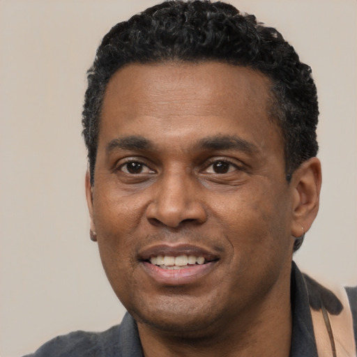Joyful black adult male with short  black hair and brown eyes