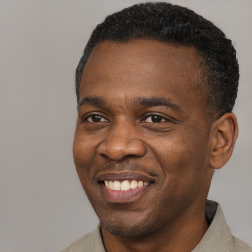 Joyful black adult male with short  black hair and brown eyes