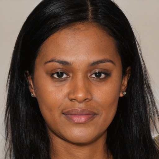 Joyful black young-adult female with long  brown hair and brown eyes
