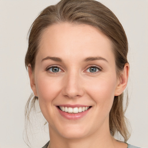 Joyful white young-adult female with medium  brown hair and grey eyes