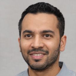 Joyful latino young-adult male with short  black hair and brown eyes