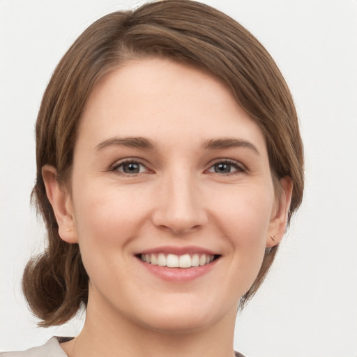 Joyful white young-adult female with medium  brown hair and grey eyes