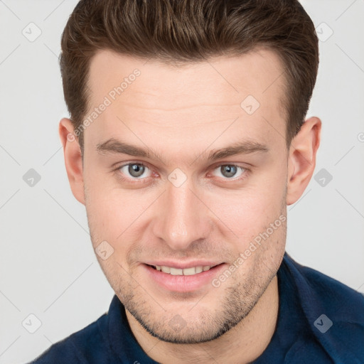 Joyful white young-adult male with short  brown hair and grey eyes