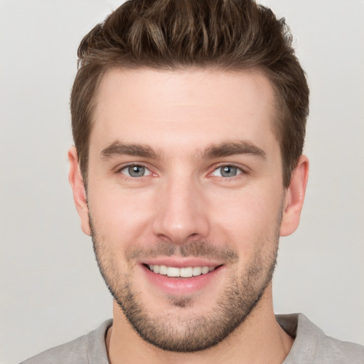 Joyful white young-adult male with short  brown hair and grey eyes