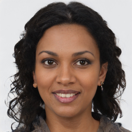 Joyful black young-adult female with long  black hair and brown eyes
