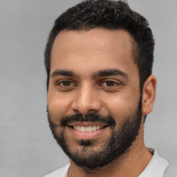 Joyful latino young-adult male with short  black hair and brown eyes