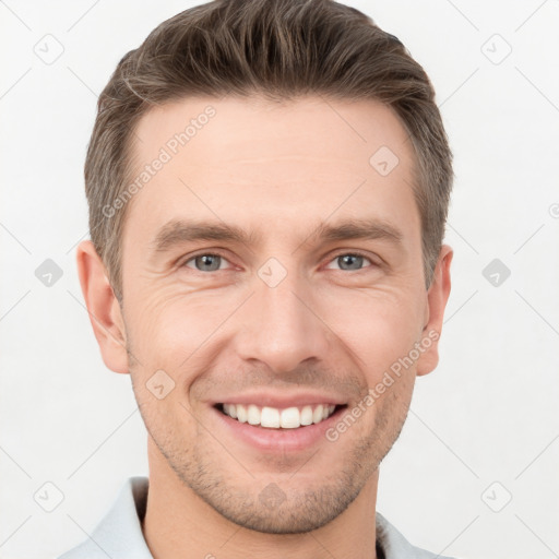 Joyful white young-adult male with short  brown hair and grey eyes