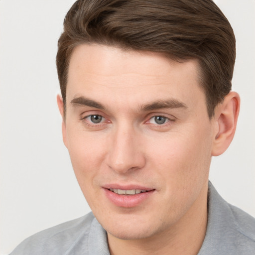 Joyful white young-adult male with short  brown hair and grey eyes