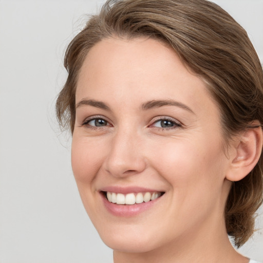 Joyful white young-adult female with medium  brown hair and grey eyes