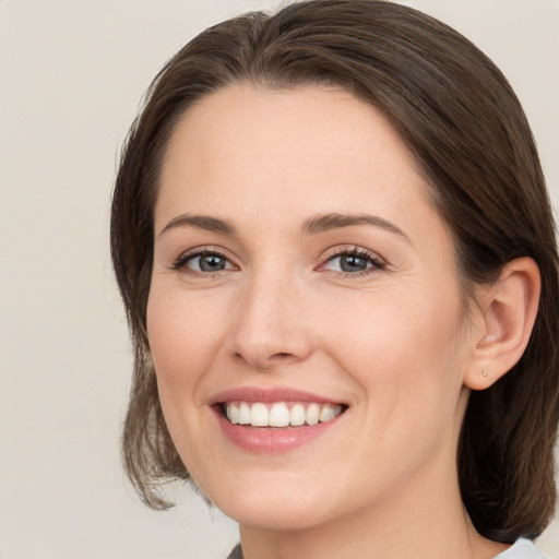 Joyful white young-adult female with medium  brown hair and grey eyes