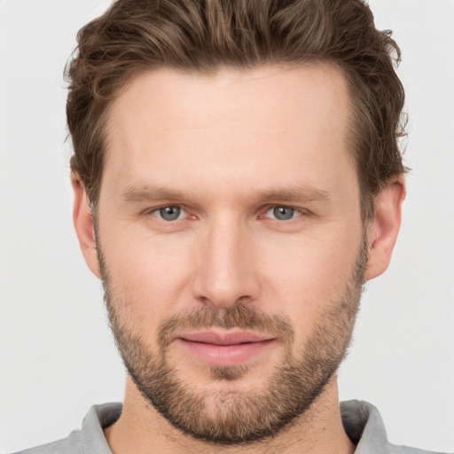 Joyful white young-adult male with short  brown hair and grey eyes