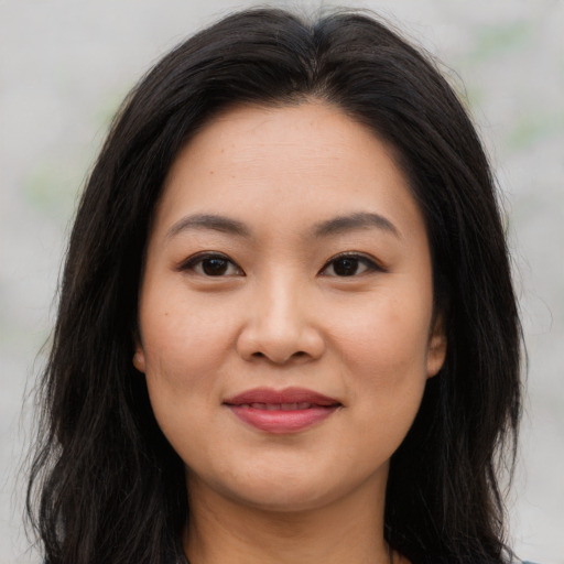 Joyful asian young-adult female with long  brown hair and brown eyes