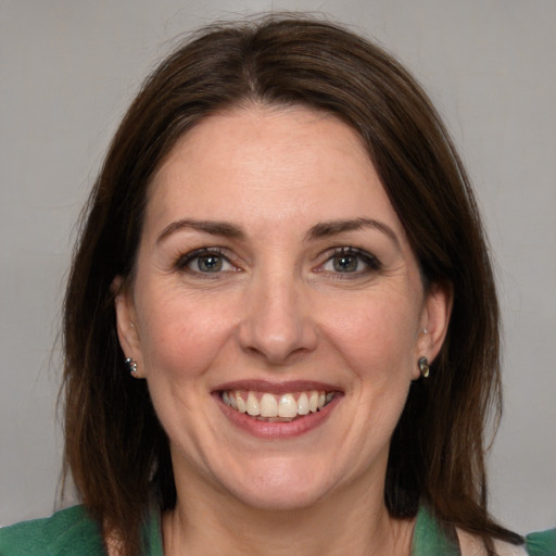 Joyful white adult female with medium  brown hair and green eyes