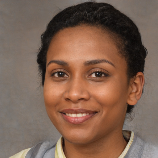 Joyful black young-adult female with short  black hair and brown eyes