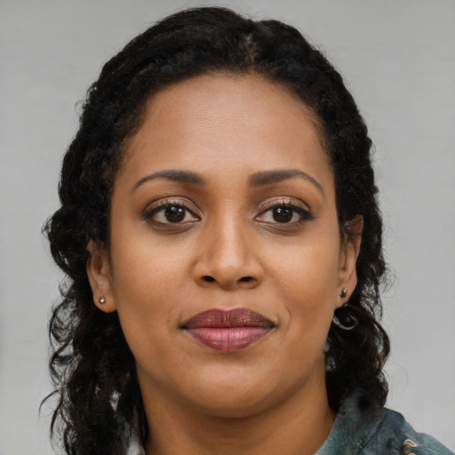 Joyful black young-adult female with long  brown hair and brown eyes