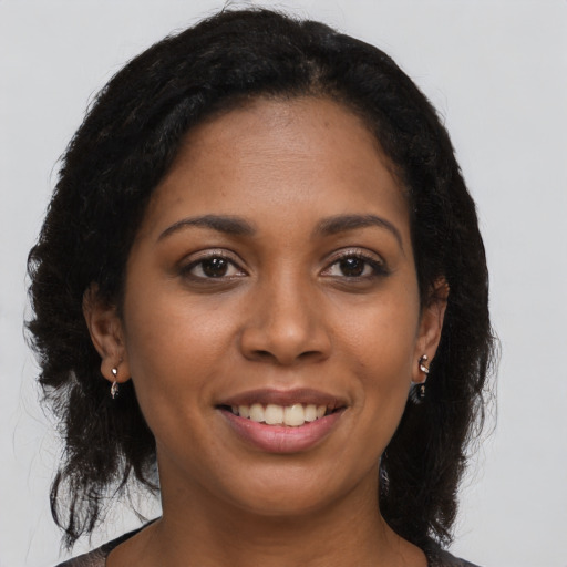 Joyful black young-adult female with long  brown hair and brown eyes