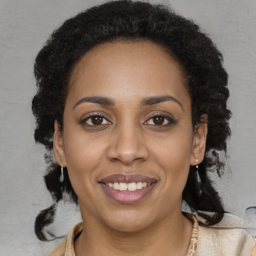 Joyful black young-adult female with long  brown hair and brown eyes