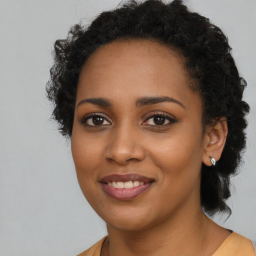 Joyful black young-adult female with long  black hair and brown eyes