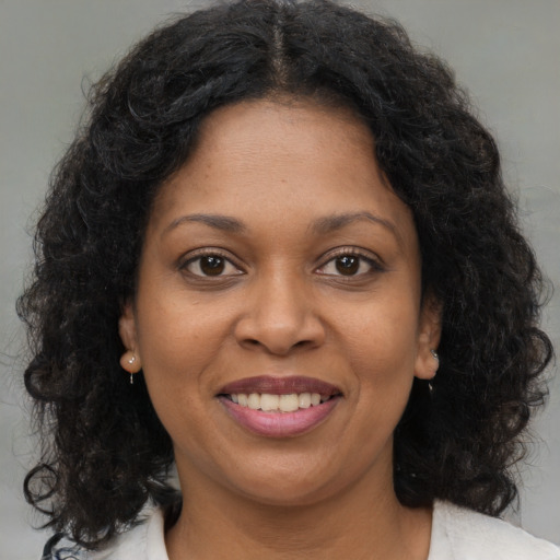 Joyful black young-adult female with long  brown hair and brown eyes