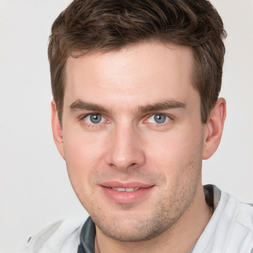 Joyful white young-adult male with short  brown hair and grey eyes