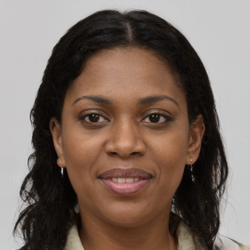 Joyful black young-adult female with long  brown hair and brown eyes
