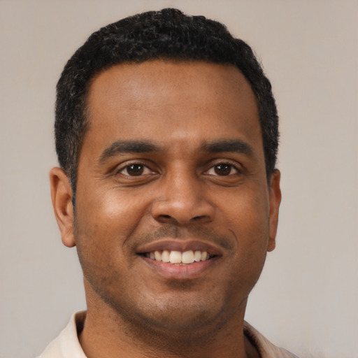 Joyful black young-adult male with short  black hair and brown eyes
