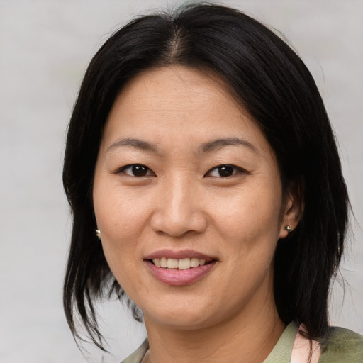 Joyful asian adult female with medium  brown hair and brown eyes