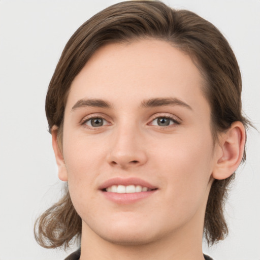 Joyful white young-adult female with medium  brown hair and grey eyes