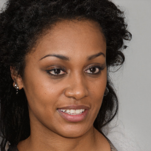 Joyful black young-adult female with long  brown hair and brown eyes