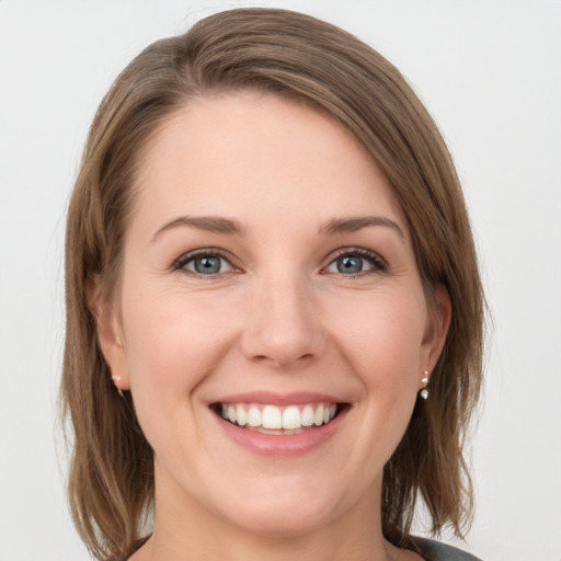 Joyful white young-adult female with medium  brown hair and grey eyes