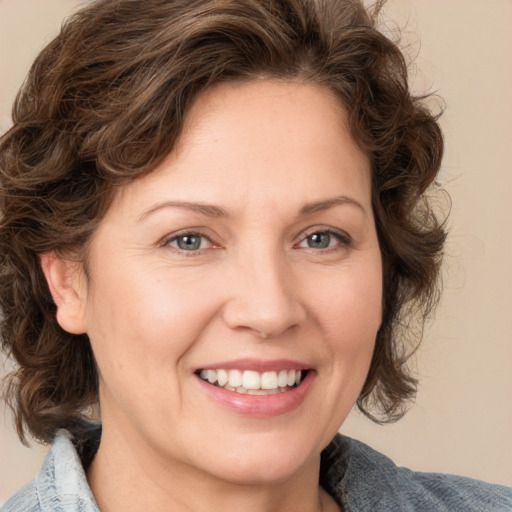 Joyful white adult female with medium  brown hair and blue eyes