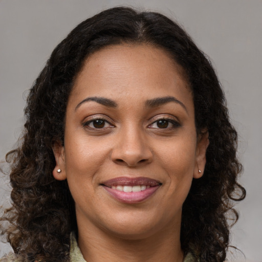 Joyful black young-adult female with long  brown hair and brown eyes