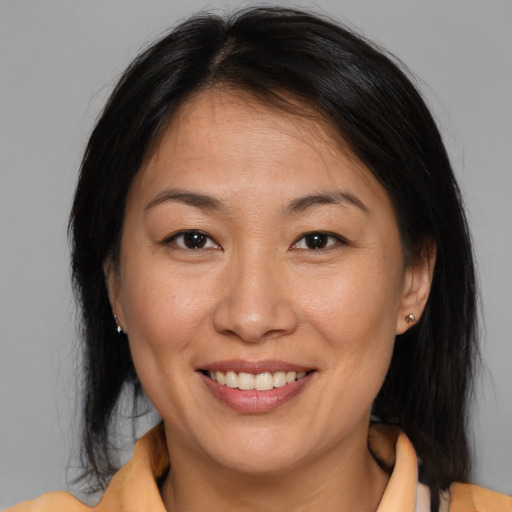 Joyful asian adult female with medium  brown hair and brown eyes