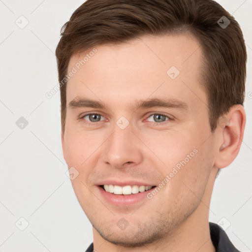 Joyful white young-adult male with short  brown hair and grey eyes