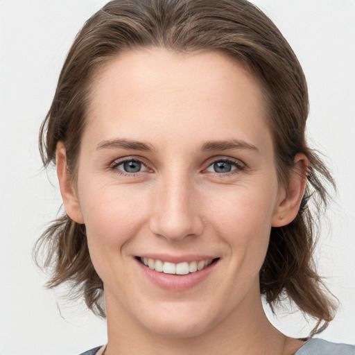 Joyful white young-adult female with medium  brown hair and grey eyes