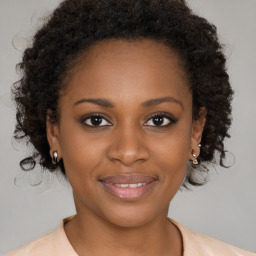 Joyful black young-adult female with long  brown hair and brown eyes