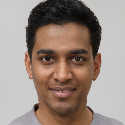 Joyful black young-adult male with short  black hair and brown eyes